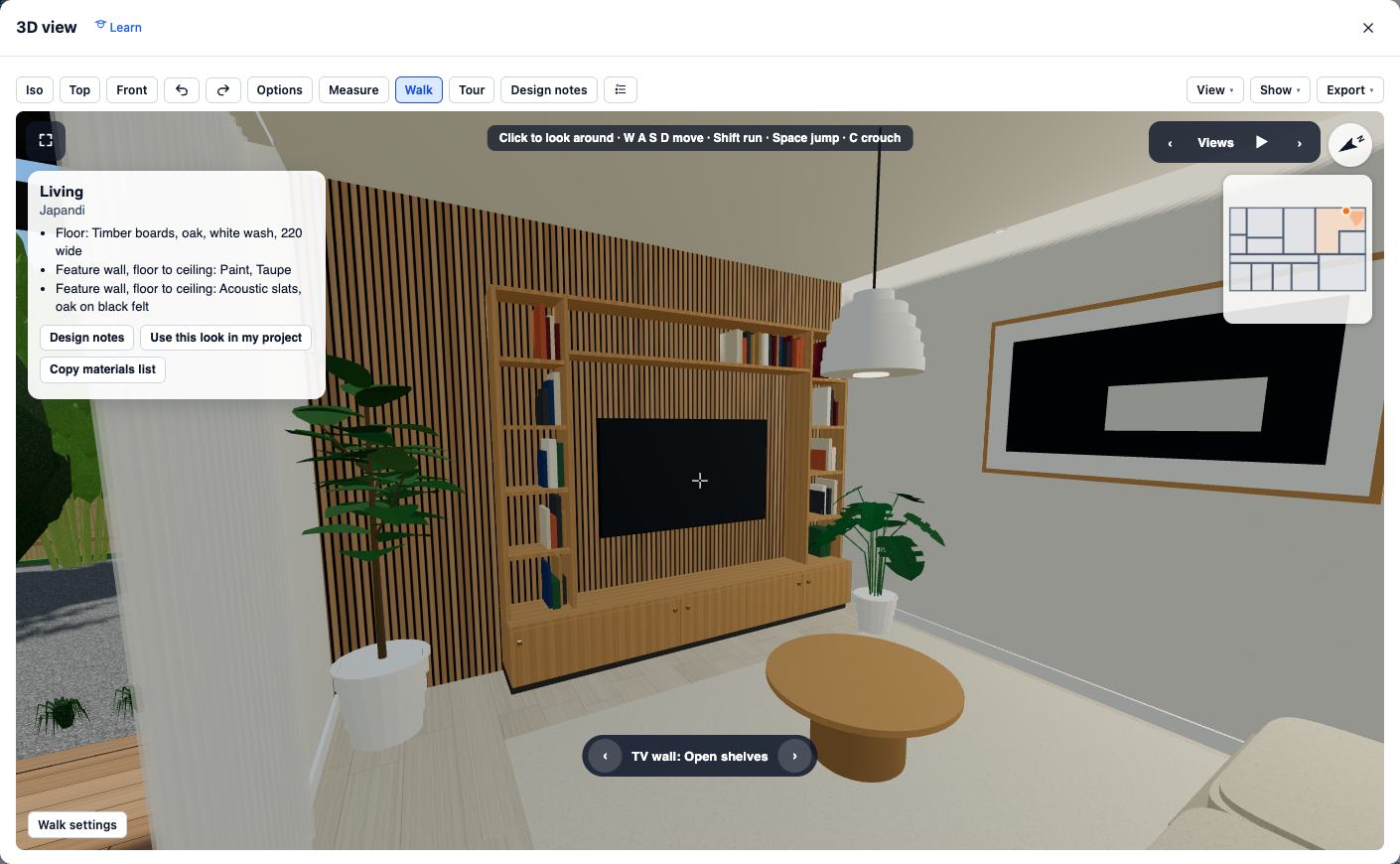 Walking through the Showroom living room: an oak media wall with open shelves of books either side of a wall-mounted TV, over oak acoustic slats, with a round coffee table in front. A label at the bottom reads TV wall: Open shelves.